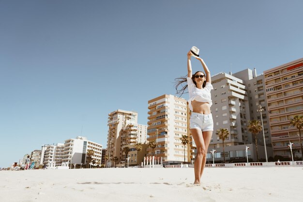 Foto donna sulla spiaggia con una bottiglia di champagne