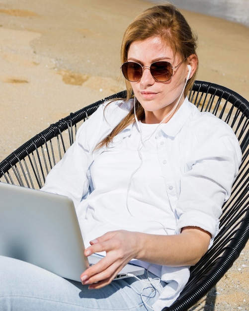 Foto donna in spiaggia che lavora al computer portatile