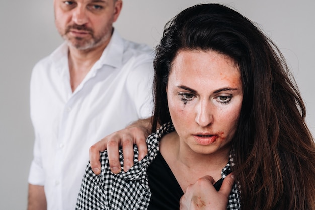 Foto una donna picchiata dal marito in piedi dietro di lei che la guardava aggressivamente. violenza domestica.