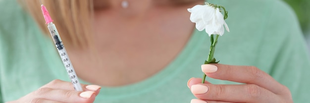 Estetista della donna che tiene la siringa con la medicina e il fiore appassito nelle sue mani closeup