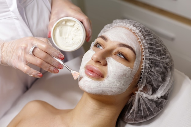 Woman at the beautician makes a mask on the face