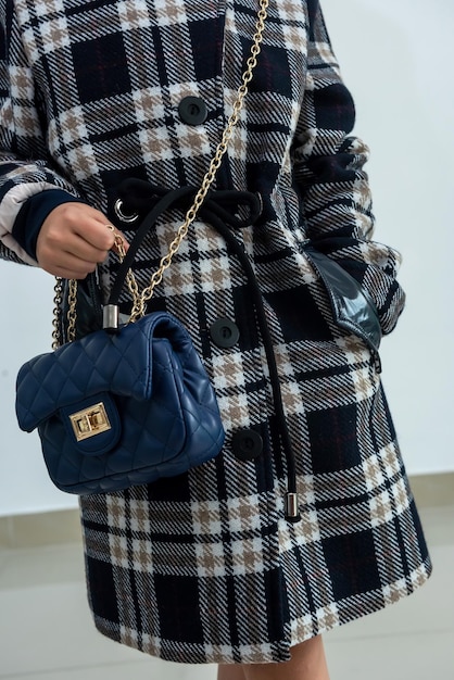 세련된 핸드백을 보완하는 무릎까지 셀에 아름다운 어두운 코트를 입은 여성. 아우터웨어 컨셉