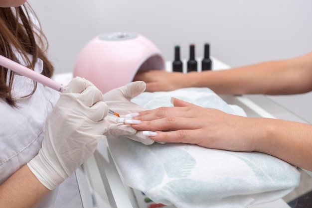 Woman in beauty center performing a nail service and beautification of hands and nails