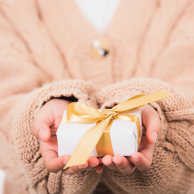 Foto mani di bellezza della donna che tengono la carta avvolta presente della confezione regalo piccola con il nastro