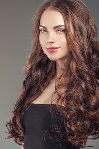 여성의 아름다움 건강한 피부와 헤어스타일 갈색 긴 머리는 어두운 배경 위에 있습니다. 스튜디오 촬영.
