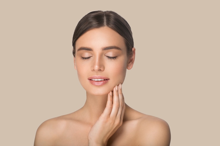 Photo woman beauty portrait touching her face. color background. brown.