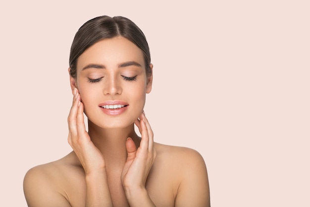 Woman beauty portrait touching her face. Color background. Pink.