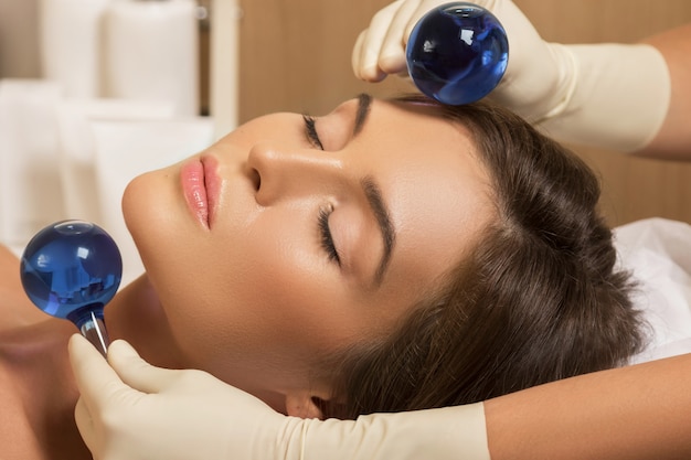 Woman in beauty salon during treatment with a cold glass balls