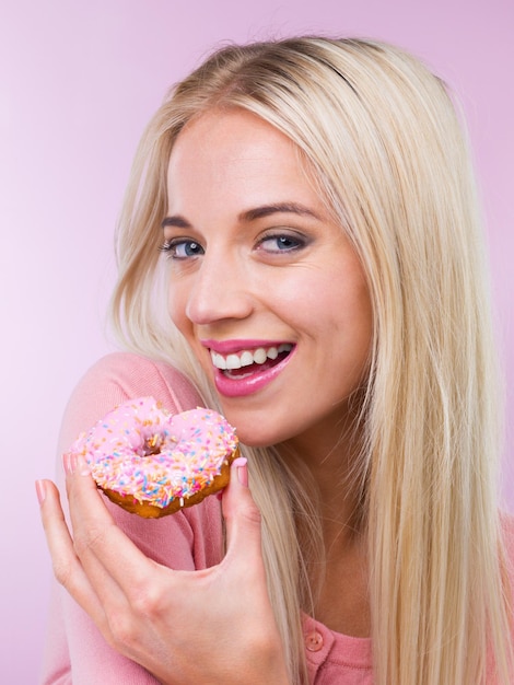 Photo woman beauty and studio portrait with donut with makeup happy and pastry by pink background girl person and model with sweets bakery product or excited smile for eating with choice for fast food