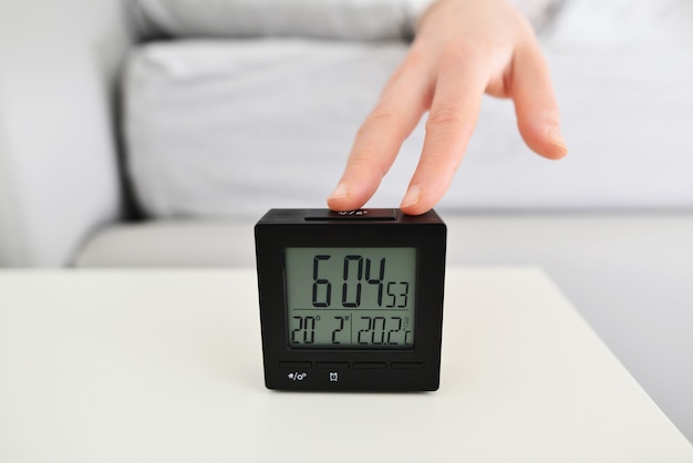 woman in bed extending hand to alarm clock