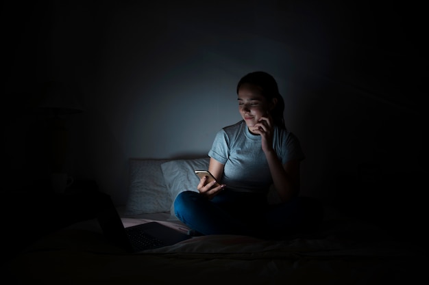 Photo woman in bed looking at smartphone at night