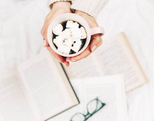 Woman in bed and read book with cup of coffee.Stylish minimalist photo.Close-up view