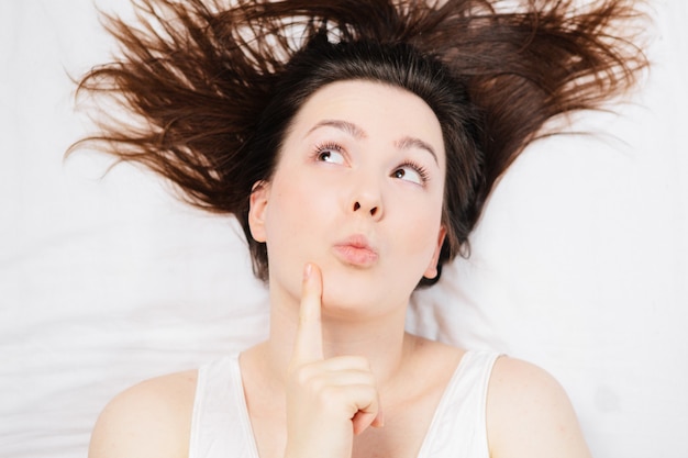 woman in bed on a white sheet with different emotions