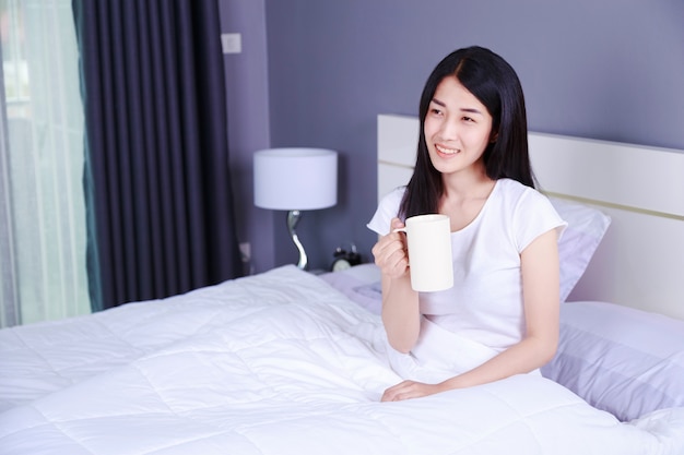 женщина на кровати с чашкой кофе в спальне