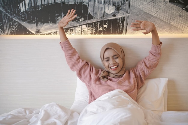 A woman in a bed with a scarf on her head and a picture of a city in the background