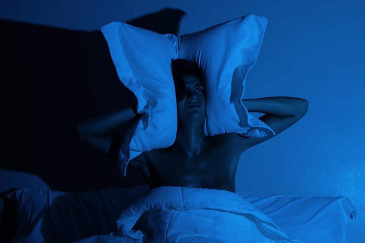 Woman in the bedroom with a pillow on her head