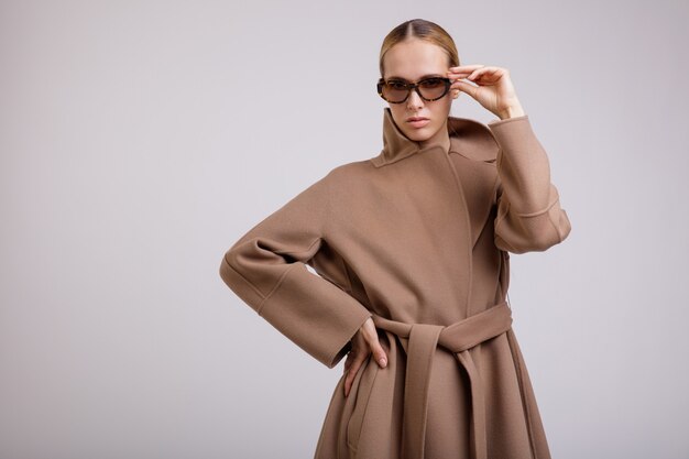 Woman in beige brown autumn coat stylish sunglasses on white background Studio Shot Slim figure