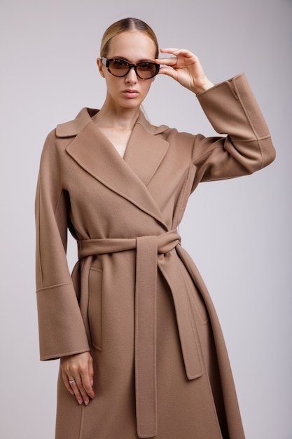 Woman in beige brown autumn coat stylish sunglasses on white background Studio Shot Slim figure