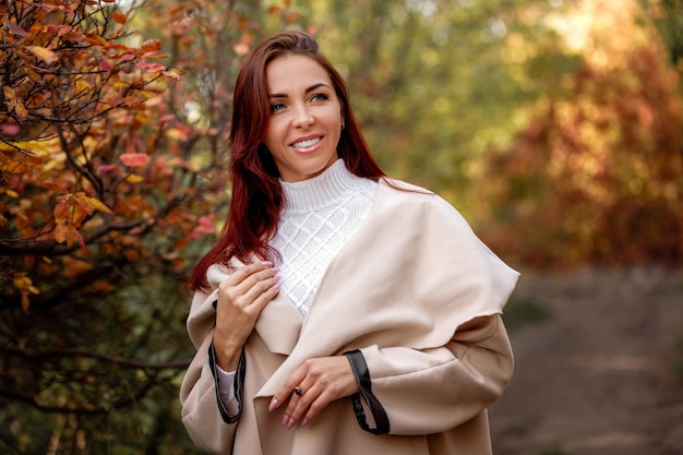 Woman in beige coat on a background of yellow autumn foliage