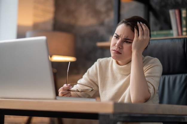 A woman in beige sweater looking tired and upset