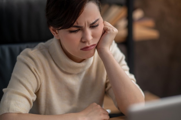 A woman in beige sweater looking tired and upset