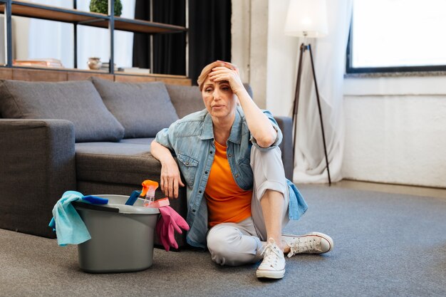 Woman being concerned. Tired distressed woman feeling sick after intense cleaning in spacious apartment