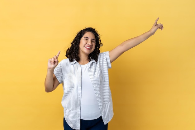 Woman being in good festive mood dancing raising hands expressing happiness