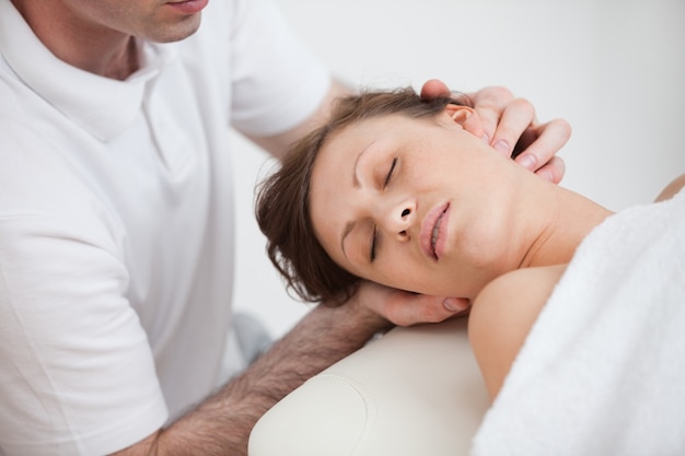 Woman being massaging by the doctor while having the head turn in the side