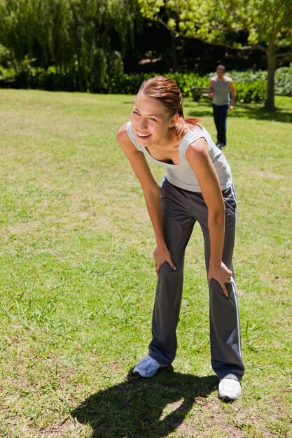 woman bending over while man is walking in the background