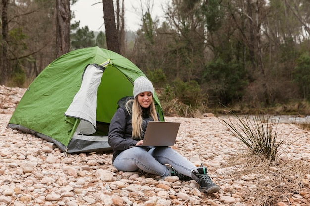 Woman beside tent with laptop