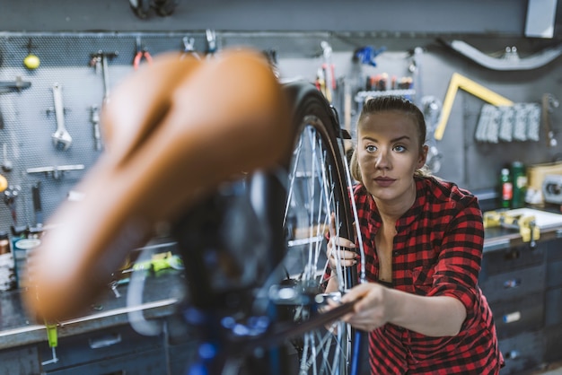 Woman bicycle engineer is repairing a bike in the workshop