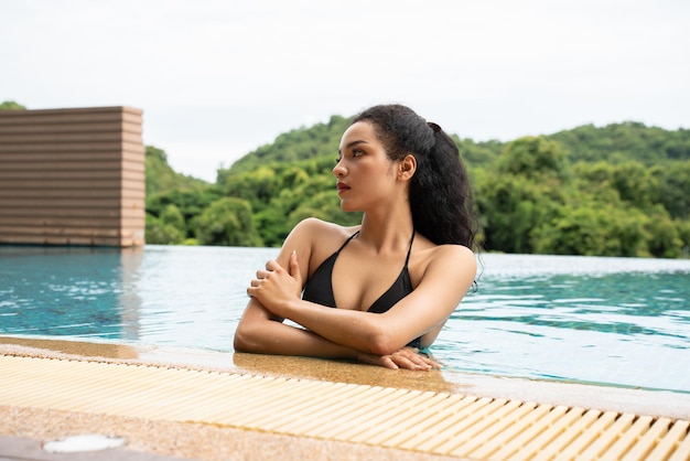 Woman in the bikini at pool Swimming pool tanned slim and shapely body Girl enjoying travel holidays at resort luxury overwater bungalow