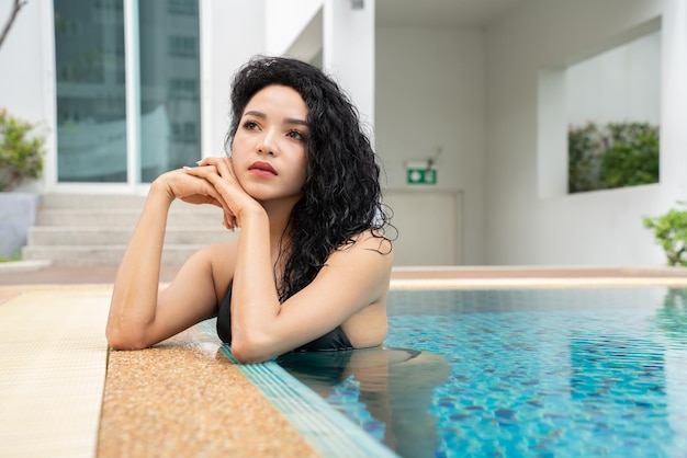 Woman in the bikini at pool Swimming pool tanned slim and shapely body Girl enjoying travel holidays at resort luxury overwater bungalow