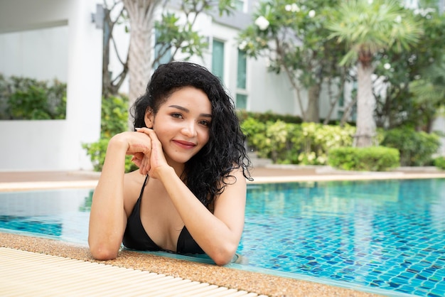 プールでビキニの女性 スイミング プールで日焼けしたスリムで形の良いボディ リゾートの豪華な水上バンガローで旅行休暇を楽しんでいる女の子