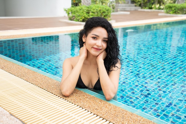 Donna in bikini in piscina piscina abbronzata corpo snello e formoso ragazza che si gode le vacanze di viaggio nel lussuoso bungalow sull'acqua del resort