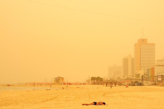 Photo woman in bikini relaxing at beach against sky in city