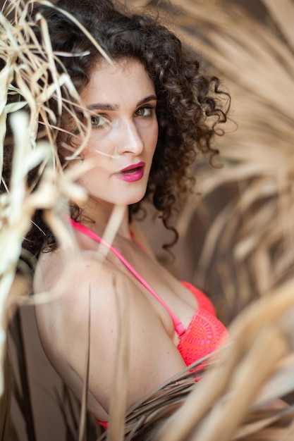 A woman in a bikini stands in the forest with a palm tree in the background