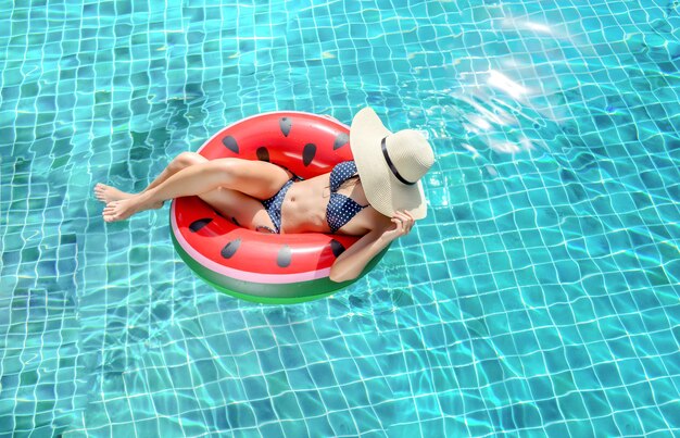 Woman bikini swimming pool on watermelon rubber ring relaxing vacation enjoying on summer season Top view