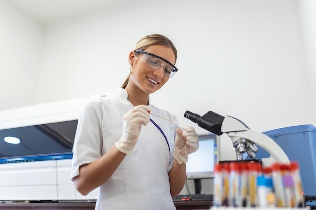 Woman biologist using micro pipette with test tube and beaker for experiment in science laboratory Biochemistry specialist working with lab equipment and glassware for development