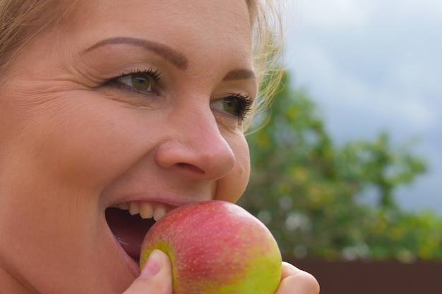 Woman  bites a fresh apple from her garden