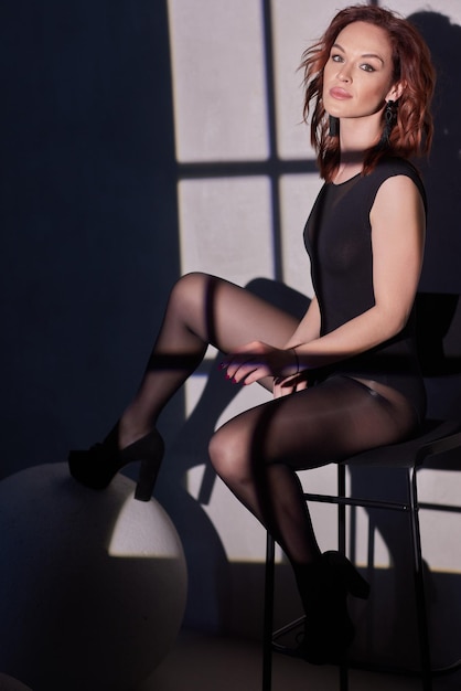 Woman in black bodysuit in the backlight of a photo studio