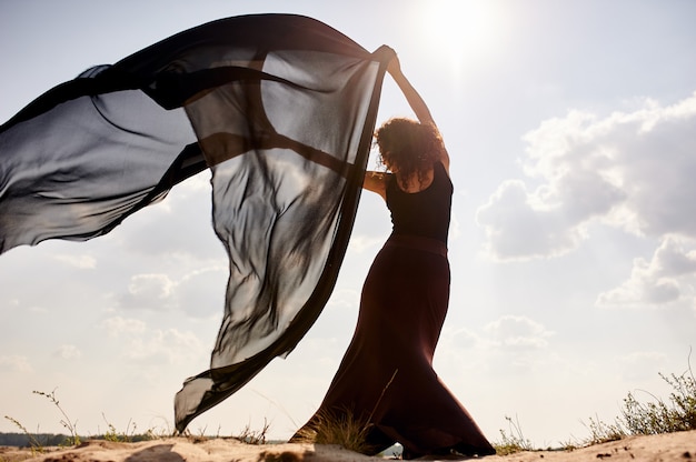 Woman in black dress dancing in the desert