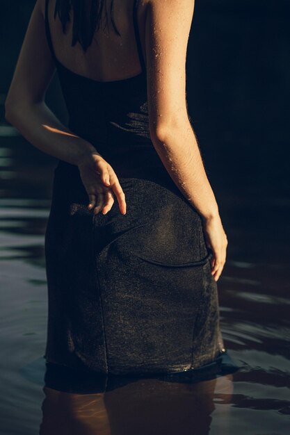 a woman in a black dress is standing in the water