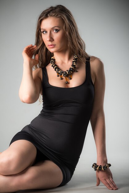 Woman in black dress and massive accessories siting and looking at camera