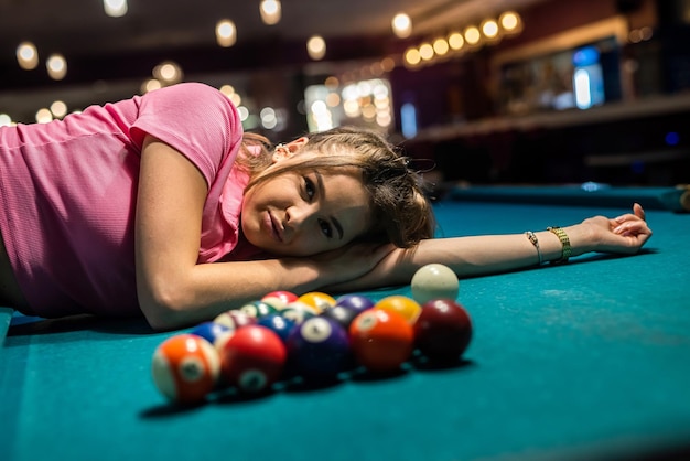 Woman in black dress near balls lying on snooker table