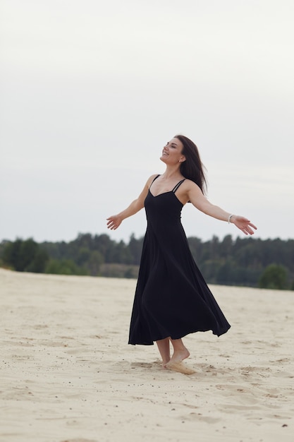 Woman in black dress smiling on nature