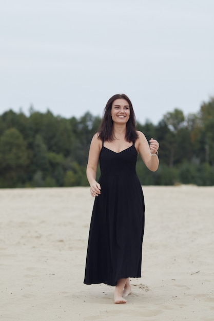 Woman in black dress smiling on nature