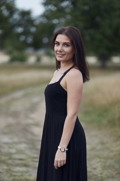 Woman in black dress smiling on nature