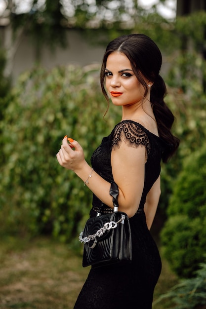 Женщина в черном платье с сумкой, на которой написано «Шанель».