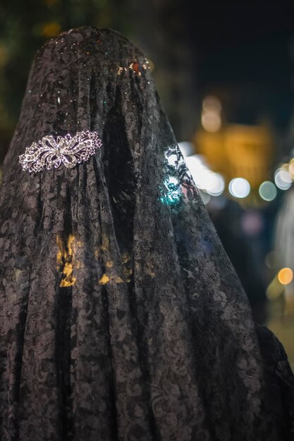 Foto una donna in abito nero con un copricapo di perline d'argento e un copricapo di perline bianche